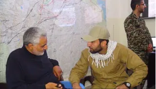 Mohammad Baqer Saad Dawood Al-Saadi sits with Qasem Soleimani in front of a wall map