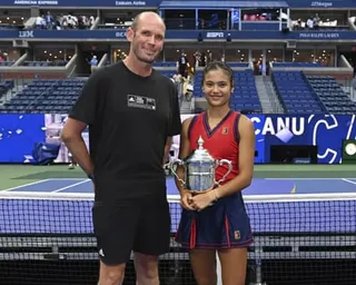 Emma Raducanu holds the US Open trophy and poses with her coach Andrew Richardson after her 2021 victory