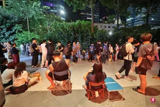 即便爱雍·乌节（ION Orchard）商场外面摆放指示牌，不允许公众隔夜排队，许多消费者还是在商场外面聚集，有的带了露营椅，有的直接坐在地上等候。 （唐家鸿摄）