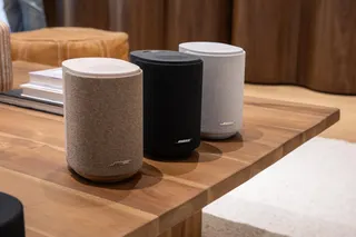 Three Bose Ultra Speakers on a wooden coffee table in beige, black, and white.
