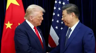 Donald Trump and Xi Jinping pictured shaking hands in front of a Chinese flag and a US flag