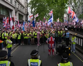 Police and crowd marshals form a line in front of protesters holding union jack and Saint George's cross flags
