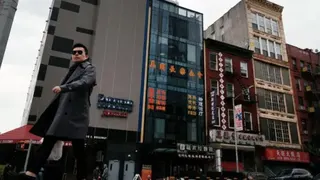 Getty Images A man in a black trench-coat walks in front of a row of buildings in Manhattan's Chinatown