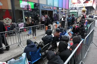 A line of people in between metal barriers outside a Swatch store