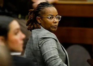 a woman looks over her shoulder while seated in court