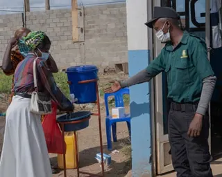 A hospital worker holds out his hand to direct a woman to a handwashing facility