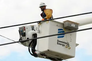 a utility worker stands in a raised basket near power lines