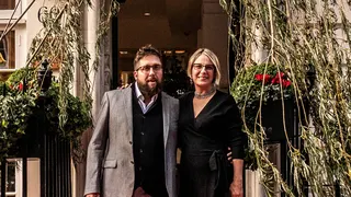 Gavin Munro and Alice Munro standing underneath one of their chairs grown from a tree in London