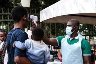 A health official uses a thermometer to screen people outside a hospital in Kampala, Uganda, on Saturday. Photo: AP