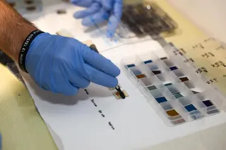 NTU researcher Edoardo Albanesi using pincers to pick up a piece of thin film at the Energy Research Institute @ NTU.