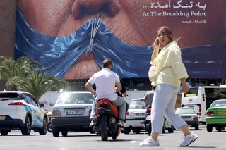 An Iranian woman walks past an anti-US billboard in Tehran