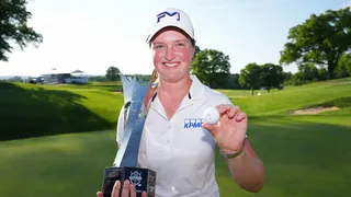 Lottie Woad smiling and holding a trophy and a golf ball
