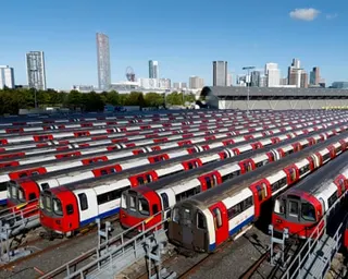Dozens of London Underground trains with red, white and blue livery parked in parallel rows at a depot