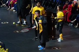 Billie Jean King tosses tennis balls to graduates