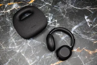 The Sony 1000X The Collexion headphones next to their carrying case on a marble surface.