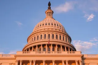 The illuminated dome of the U.S. Capitol Building rises against a blue evening sky