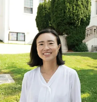 A woman in a white blouse smiling for a photo.