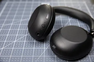 The Sony 1000X The Collexion headphones in black on a pale blue grid surface.