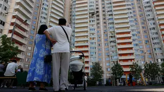 arias personas permanecen frente a un edificio de apartamentos dañado durante un ataque ucraniano con drones en el transcurso del conflicto entre Rusia y Ucrania, en Krasnogorsk, en la región de Moscú, Rusia, el 17 de mayo de 2026.