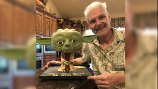 Tom Kane posing with a Yoda figurine.