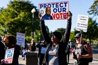 a person holds a sign that reads 'protect our vote'