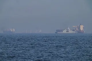 A patrol boat sails near a tanker.