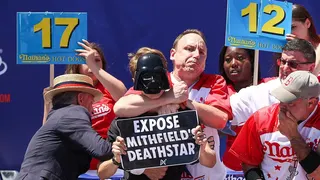 Joey Chestnut grabbing a protester by the neck at Nathan's Hot Dog Eating Contest in Coney Island