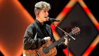 Singer Jack Avery performs onstage with a guitar during a live performance