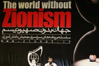 Mahmoud Ahmadinejad delivers a speech in front of a banner calling for a world without Zionism