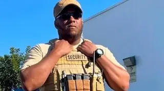 Islamic Center of San Diego Amin Abdullah stands outside wearing black sunglasses and a beige cap, T-shirt and tactical vest.