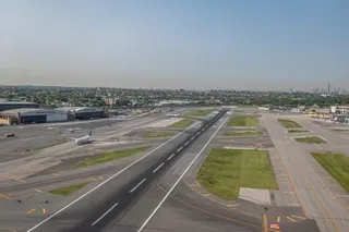 Aerial view of LaGuardia Airport runways and taxiways with green grass areas between them, and aircraft visible