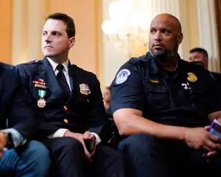 two men look to the side while seated
