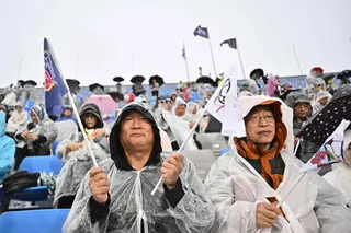 由来自韩国200多个民间团体、约3000人组成的拉拉队，在比赛期间身穿雨衣为两队加油助威。也有韩国球迷赛前说，会更支持朝鲜队，毕竟她们是远道而来。（法新社）