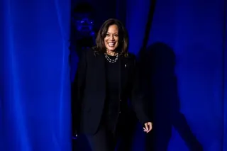 a woman smiles as she walks in front of blue curtains