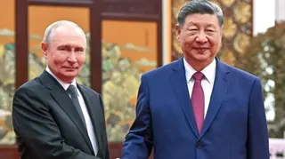 普京（左）與習近平（右）在北京人民大會堂茶敘時握手供媒體記者拍攝；普京身穿深色西裝、白色襯衣，結波爾卡圓點領帶；習近平身穿海軍藍色西裝、白色襯衣，結紅色領帶（20/5/2026）