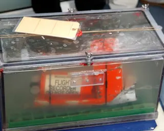 The cockpit voice recorder, one of two flight recorders from the Rio-Paris Air France flight that crashed in 2009. It is a bright orange device in a locked transparent case, submerged in water.