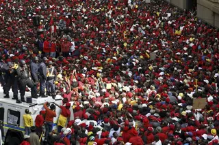 Police keep watch as South African state workers seeking higher wages take part in a strike in Johannesburg