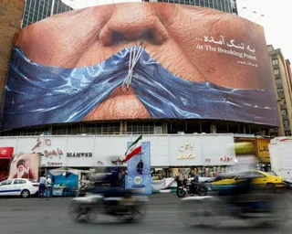 People driving past an anti-US billboard in Tehran.