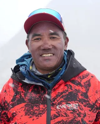 A smiling Kami Rita Sherpa wearing a cap