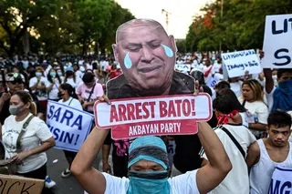 An activist displays a sign calling for the arrest of Senator Ronald “Bato” dela Rosa, on May 13 outside the Philippine senate. Photo: Reuters