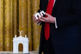 A man holds small models of an arch