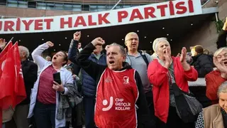AFP via Getty Images Men and women in red bibs stand outside the headquarters of Turkey's Republican People's Party