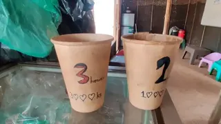 在一間簡陋的房間內，櫃檯上擺放着兩個紙杯，上面標示三小時及一小時上網服務的價格。牆邊放置着低矮的塑膠椅。