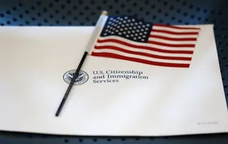 A small American flag rests on a document from U.S. Citizenship and Immigration Services
