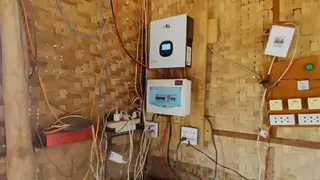 敏的咖啡店一角。店內以編織竹牆構成，牆上安裝了兩個電源裝置，連接的電線自上方垂下，延伸至地面附近。