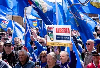 Protesters hold signs and flags to promote Alberta's independence.