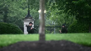 A Secret Service agent carrying a rifle on the White House grounds.