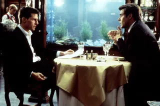 Tom Cruise faces Henry Czerny across a restaurant table in front of an aquariam