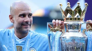 A smiling Pep Guardiola alongside the Premier League trophy in a previous season