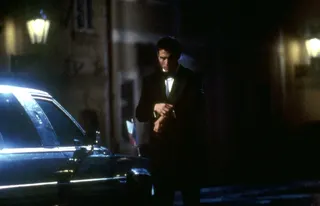 Tom Cruise in a dinner jacket checks his watch on a nighttime street